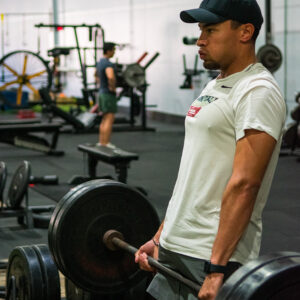 A male professional sprinter performing a barbell deadlift.