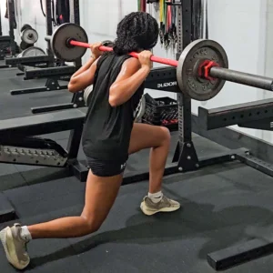 A female athlete performing barbell split squats.