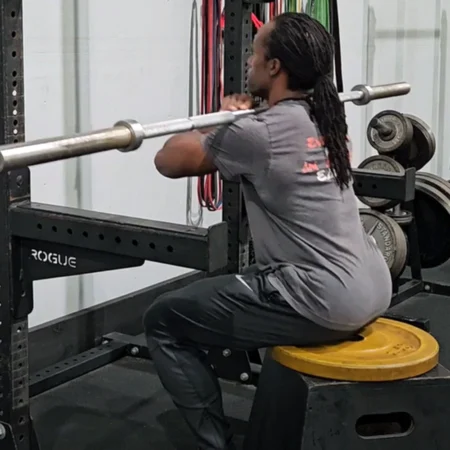 A male athlete performing a seated barbell squat.