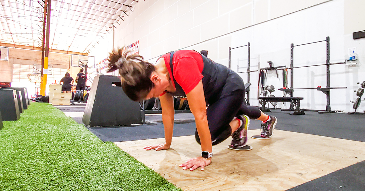 A woman doing a bodyweight workout in a gym.